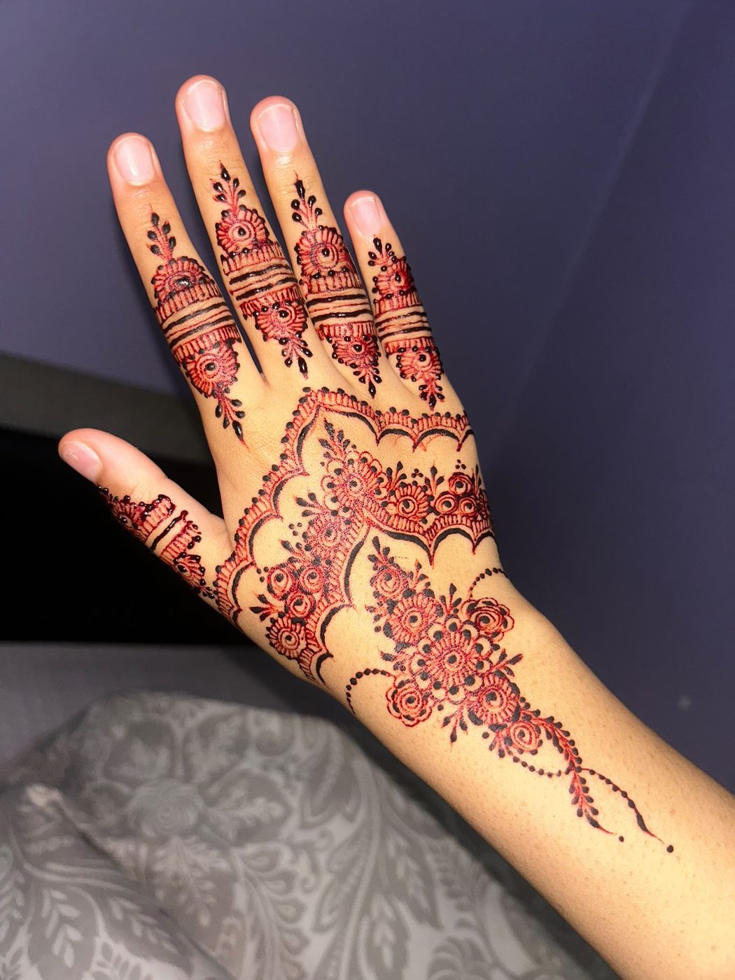 Rich red bridal henna across fingers and hand